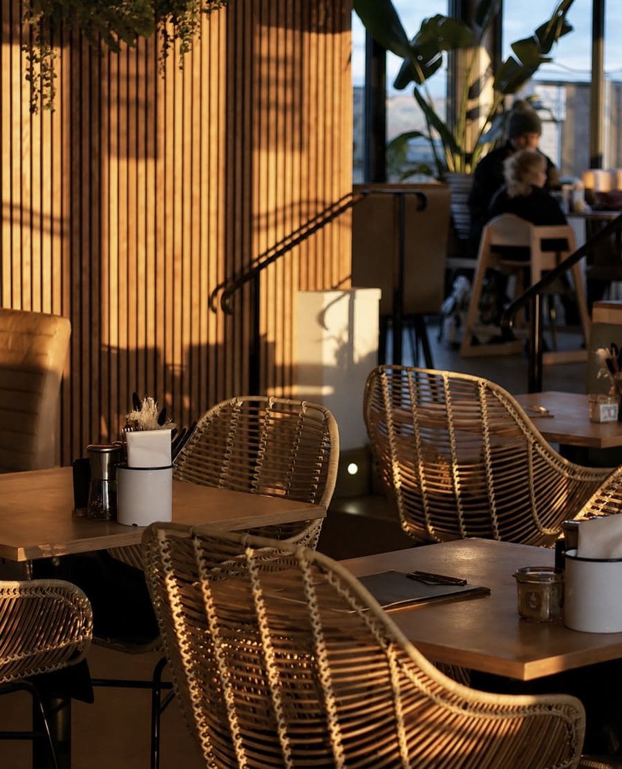 Rattan chairs and timber slat walls inside Vistas, lit by low golden-hour sun
